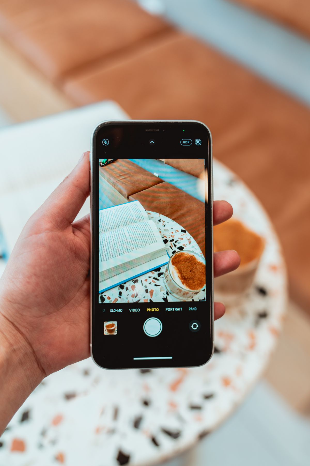 コーヒーのそばでスマートフォンを使う手元